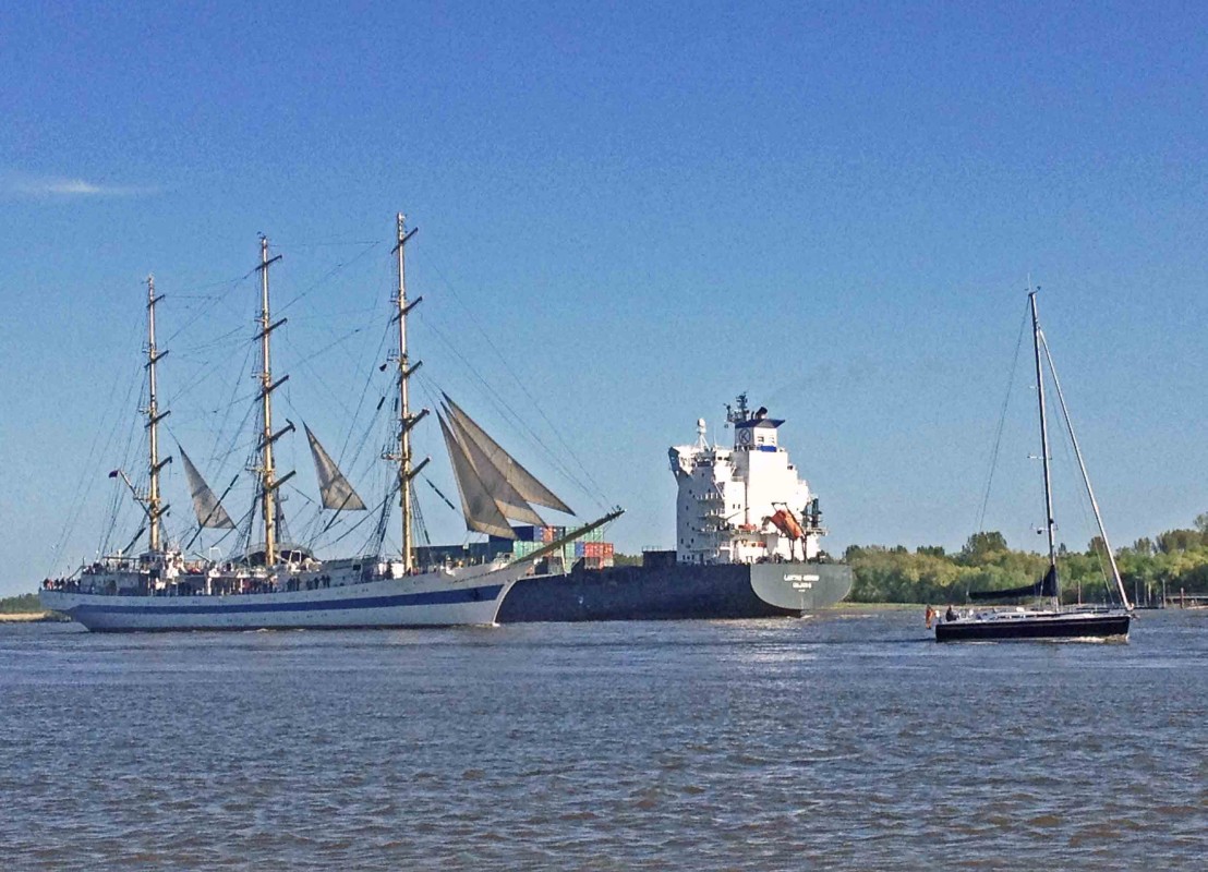 Dreimaster Mir, ein russisches Segelschulschiff, passiert einen Containerfrachter auf der Elbe